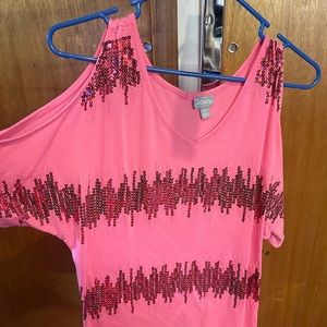 Pink with sequins on the shirt and is open on the sleeves